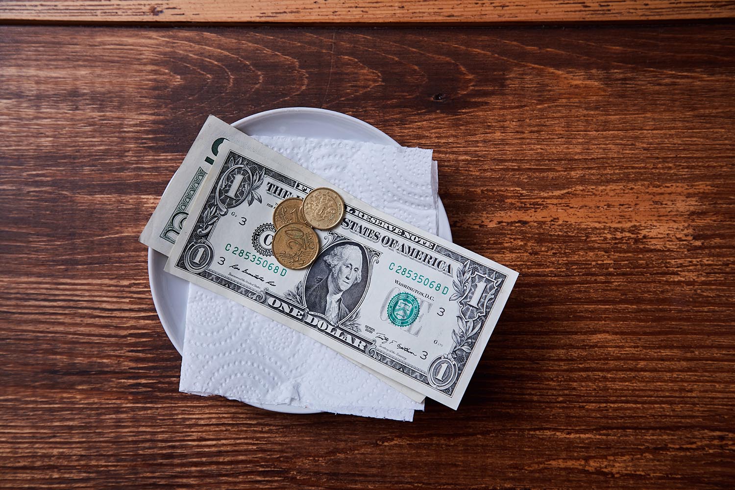 Dollar bills and coins sitting on a tipping tray.